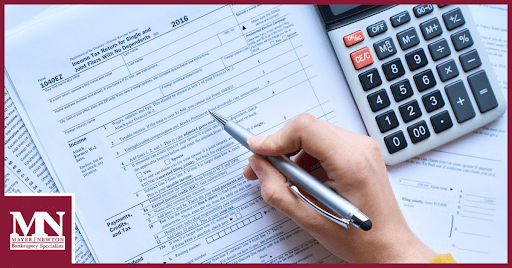 A person looking at paperwork and a calculator