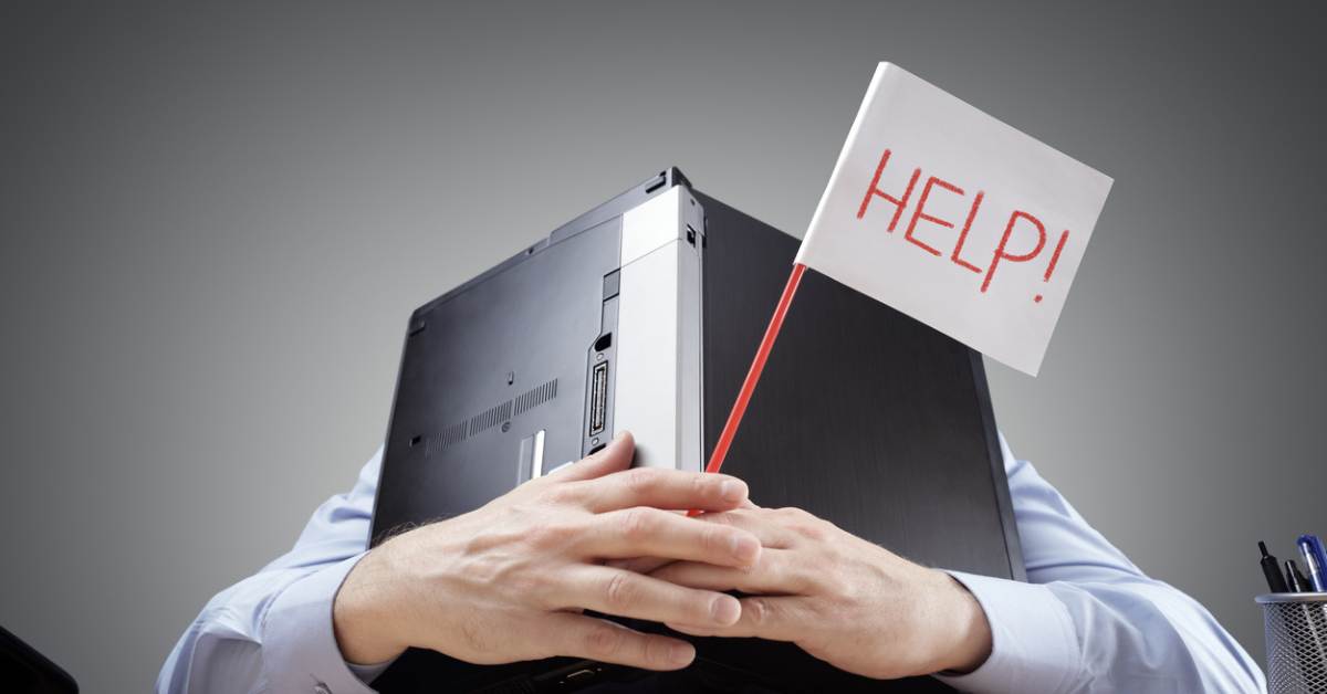 Businessman burying his head uner a laptop asking for help